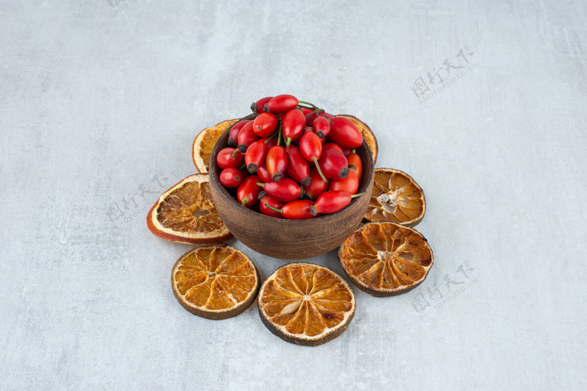 切片在石头表面放一碗玫瑰果和干橘子片玫瑰果天然橙子