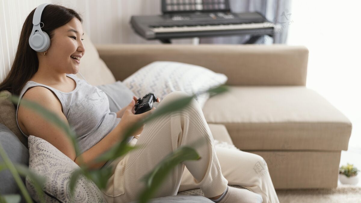 耳机在沙发上玩电子游戏的女孩爱好中镜头设备