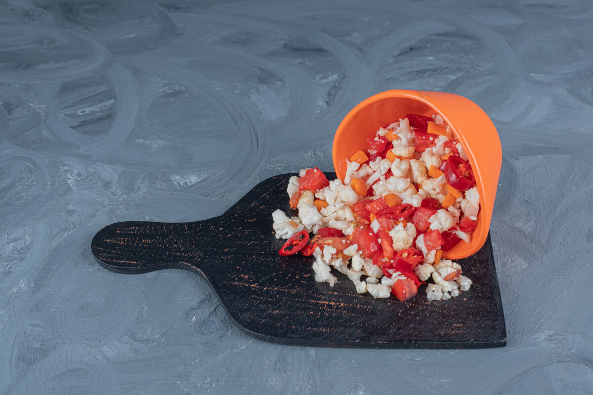 可口胡椒和花椰菜沙拉从碗里倒出来 放在大理石桌上的黑木板上美味饮食美味