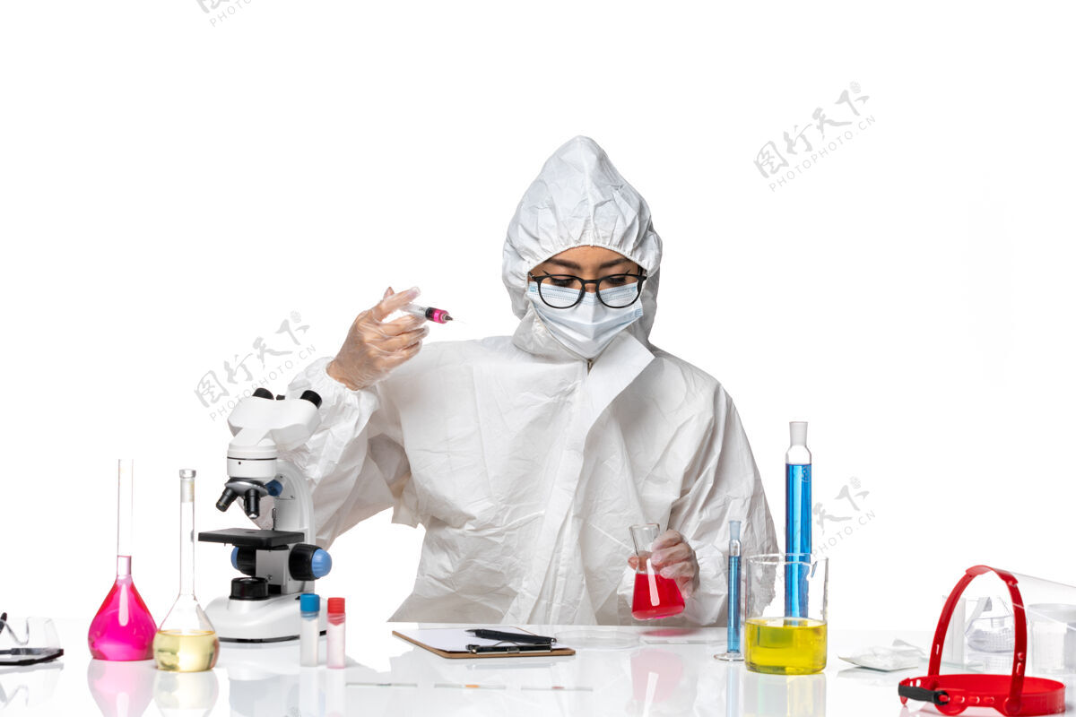女化学家前视图穿着特殊防护服的女化学家正在用浅白色背景的化学病毒实验室的溶液工作灯光视图医学
