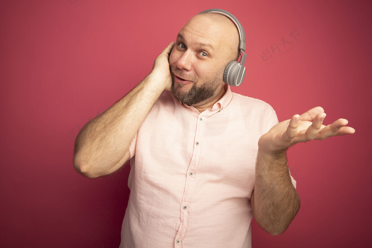 中年微笑的中年秃头男子身穿粉色t恤 戴着耳机摊开双手家伙秃头人