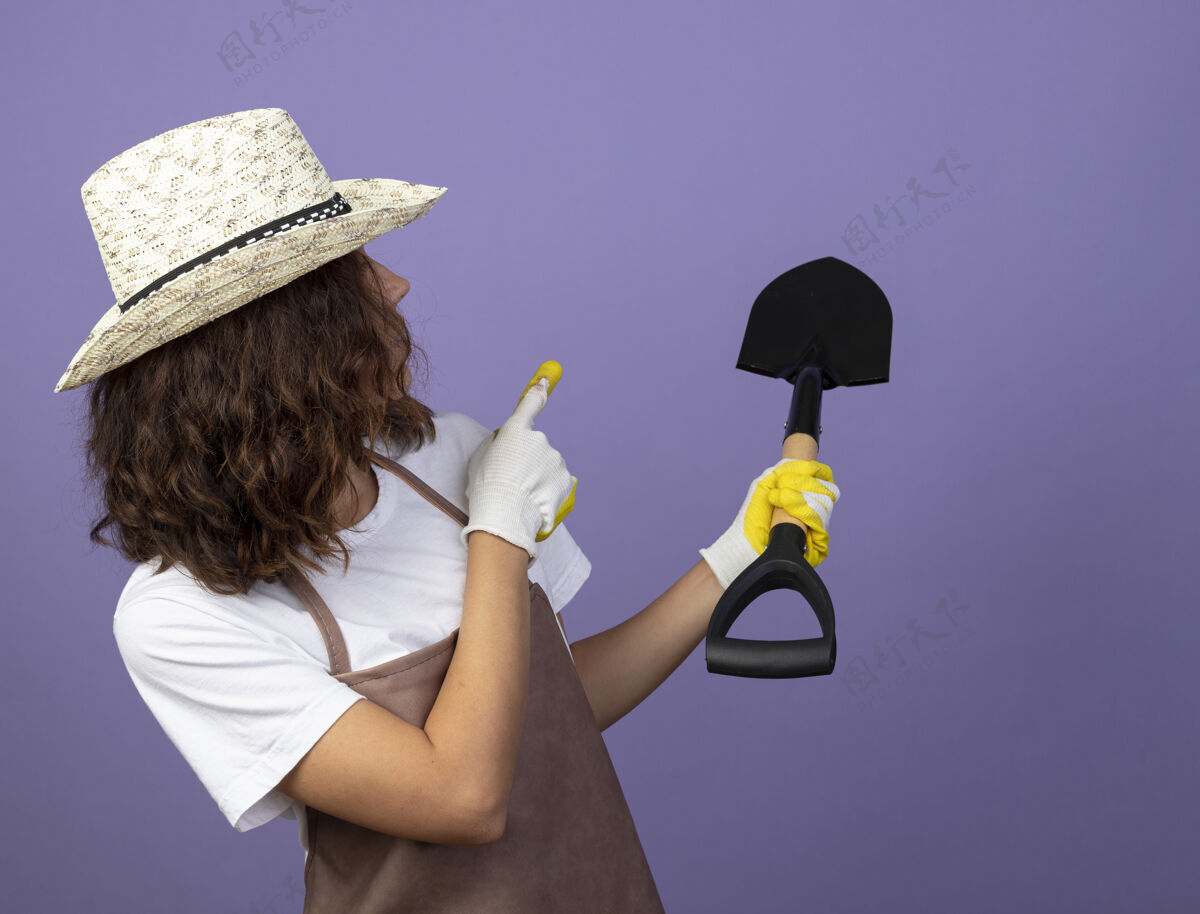 点看着后面年轻的女园丁穿着制服戴着园艺帽和手套点着铲子在后面穿女成人