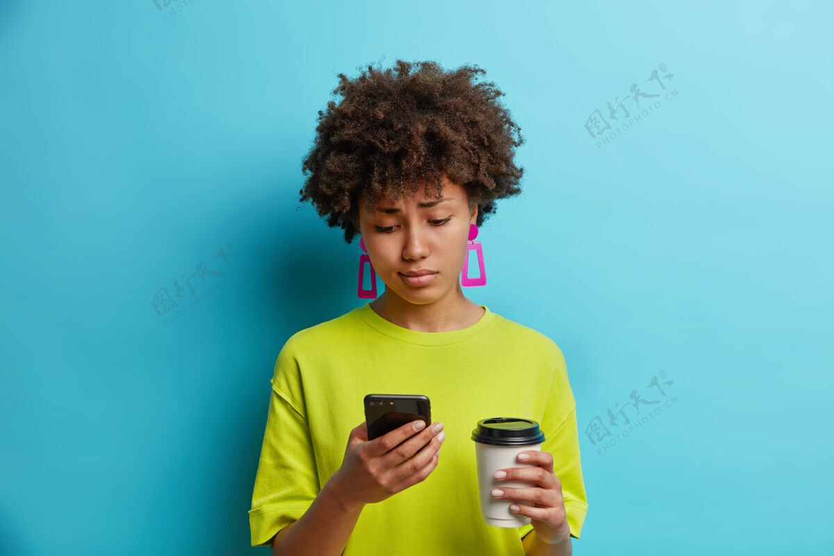 打字不高兴的年轻美籍黑人美女伤心地看着智能手机电话杯子忧郁