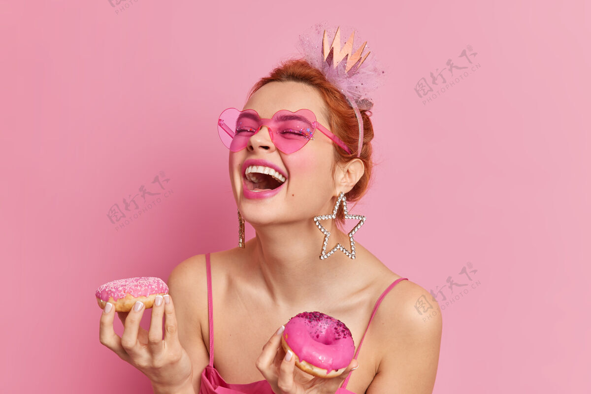 积极正面红发白种女人画像笑得大声张着嘴有乐观的心情拿着两个甜甜圈衣服甜甜圈蛋糕