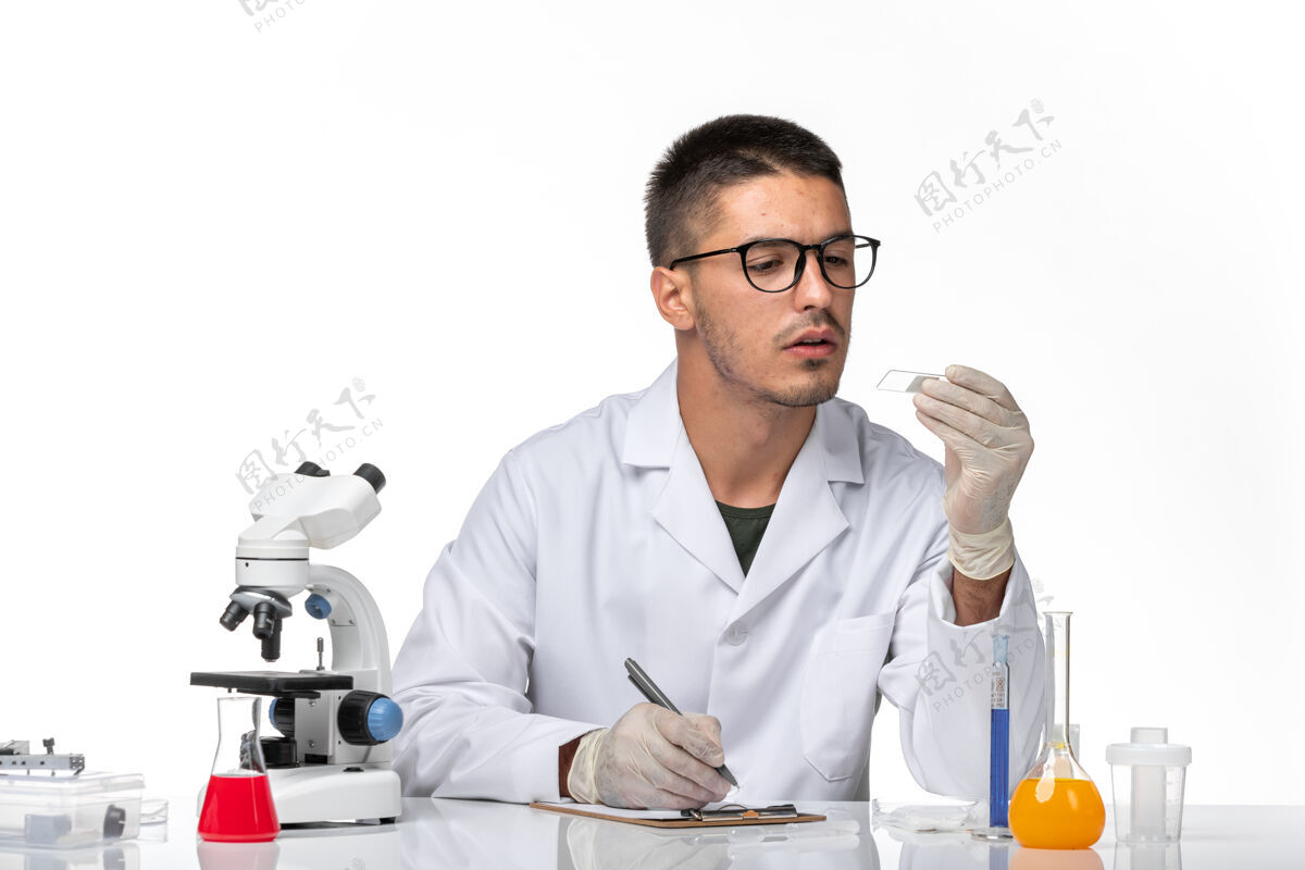 观点前视图穿着白色医疗服的男医生在白色空间上使用解决方案专业实验室外套健康