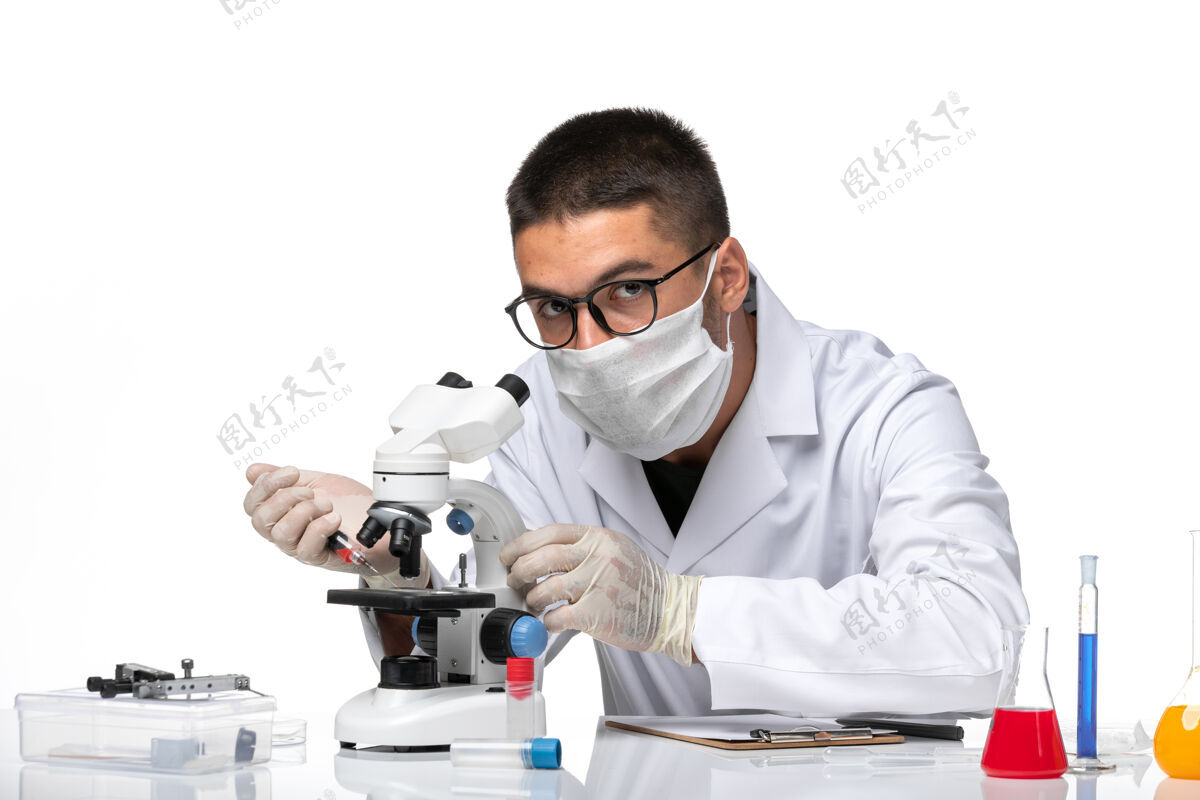 实验室外套正面图男性医生穿着白色医疗服 戴着面罩 因为科维德在一个白色的空间里用显微镜工作专业大流行医生