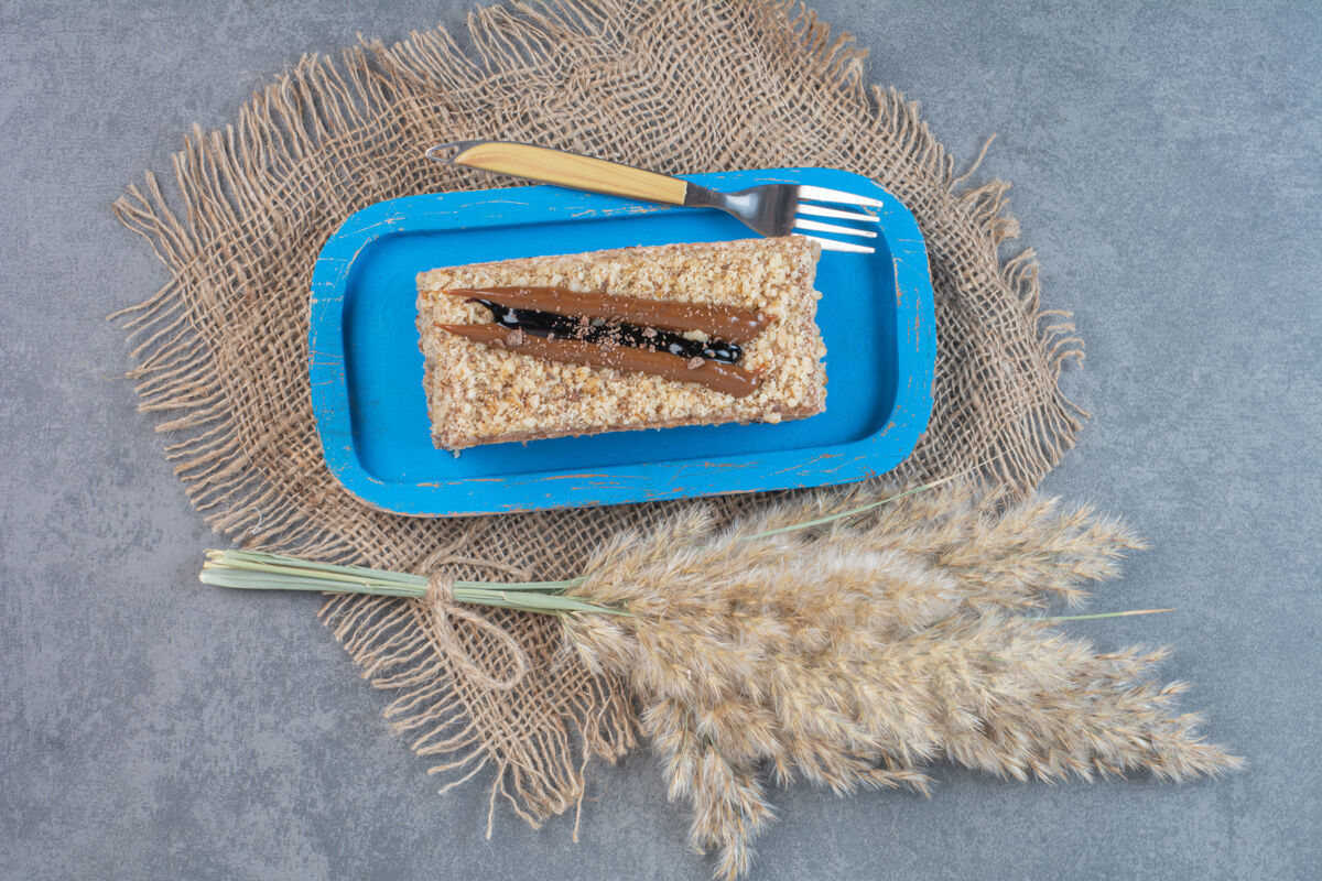 粗麻布一块奶油蛋糕放在蓝色盘子里 用叉子叉着美味叉子派