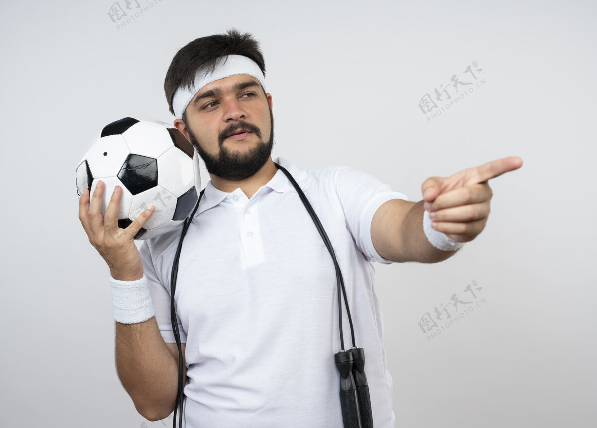 点喜欢运动的年轻人戴着头带和腕带 肩上系着跳绳 在隔离的白色墙壁上拿着球点绳持有肩膀