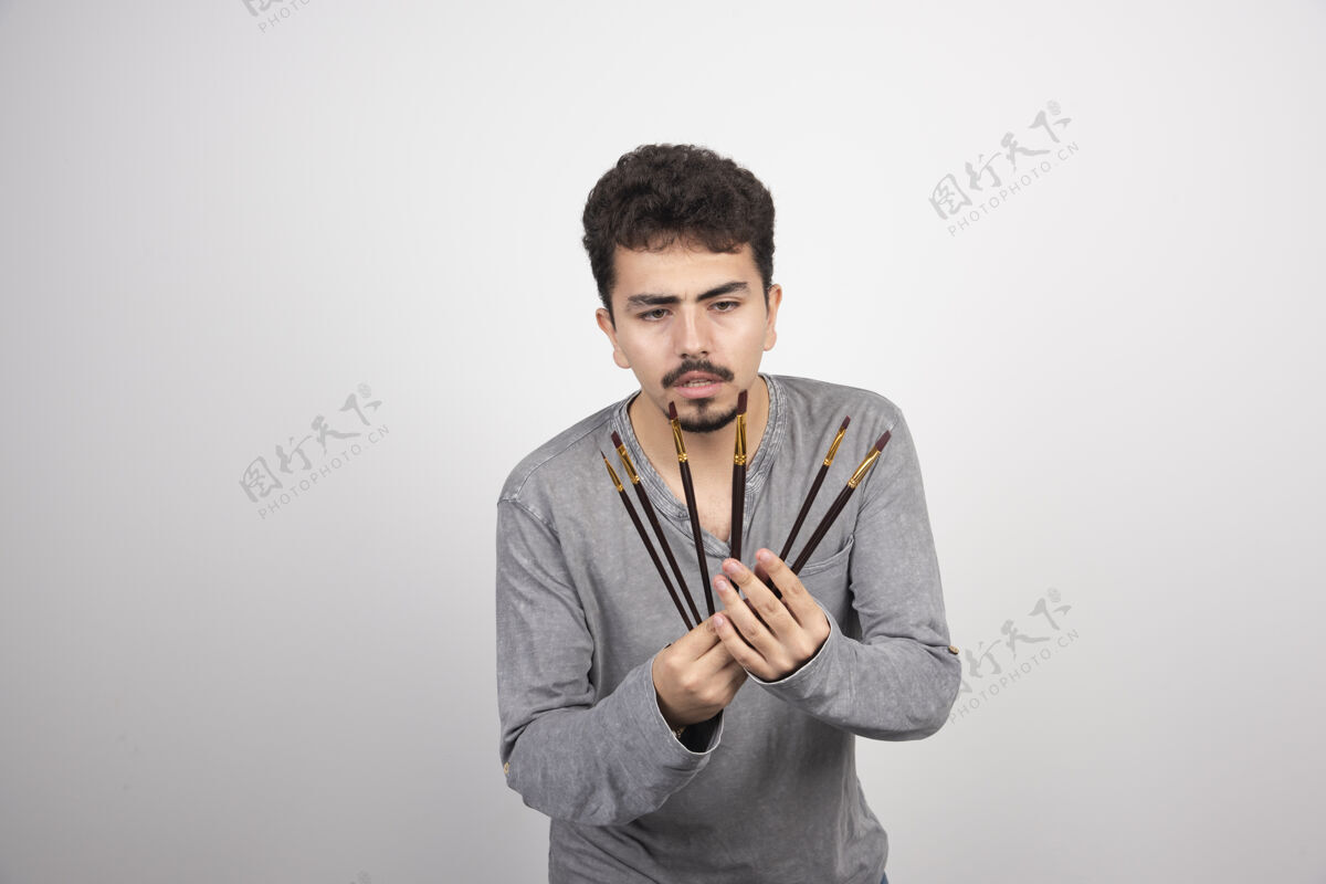 男人艺术家拿着他的一套新的专业画笔年轻装备休闲