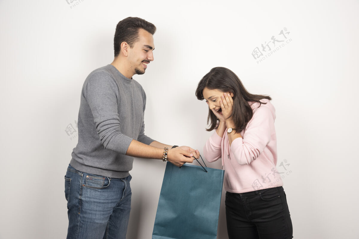 女人一个年轻的女人看着她男朋友送她的礼物很高兴女人包装男人
