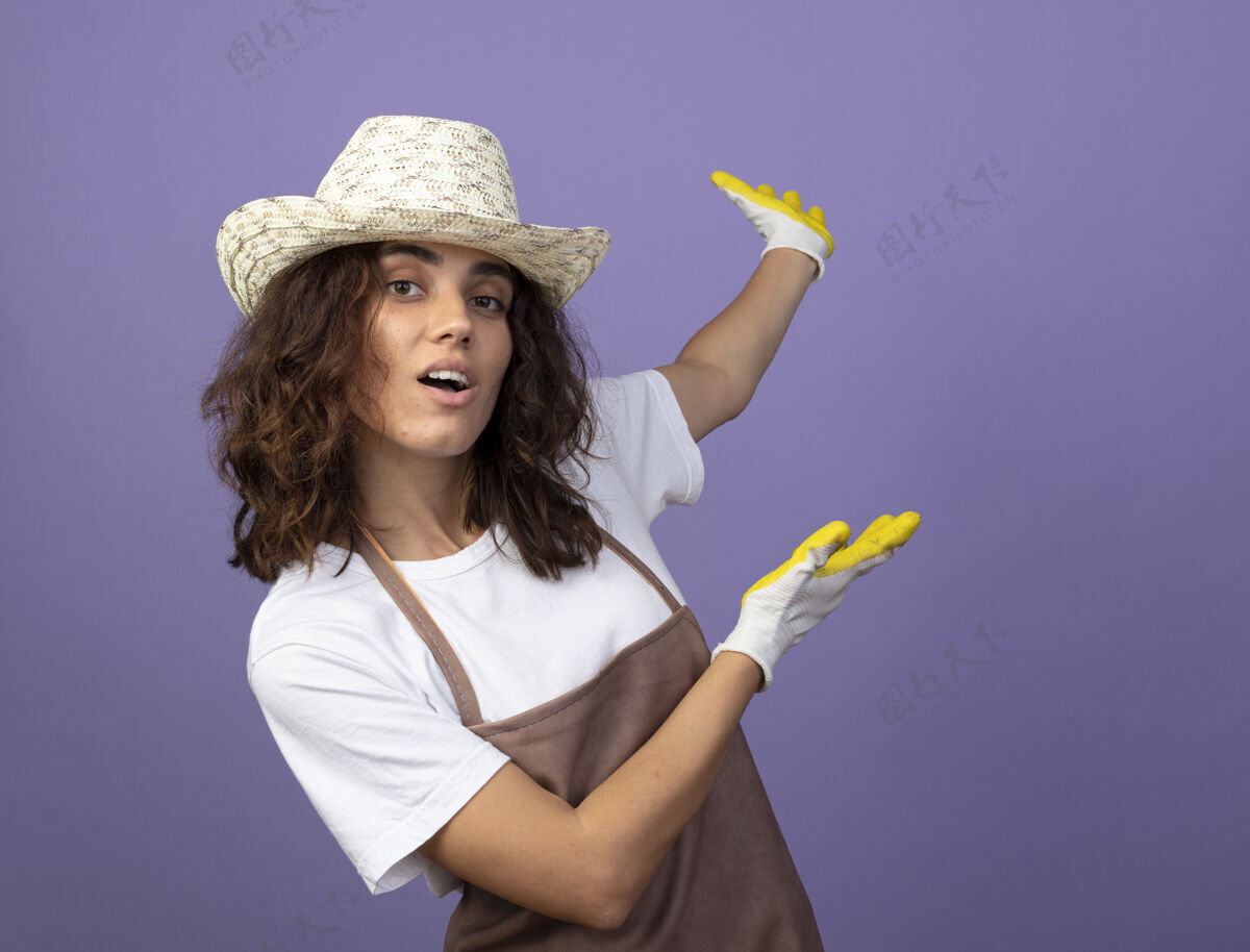 人印象深刻的年轻女园丁穿着制服戴着园艺帽和手套分在后面女人穿点