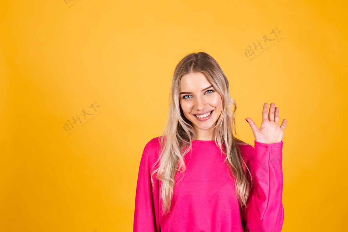 站立黄色墙上穿粉红色上衣的漂亮欧洲女人手喜悦表情