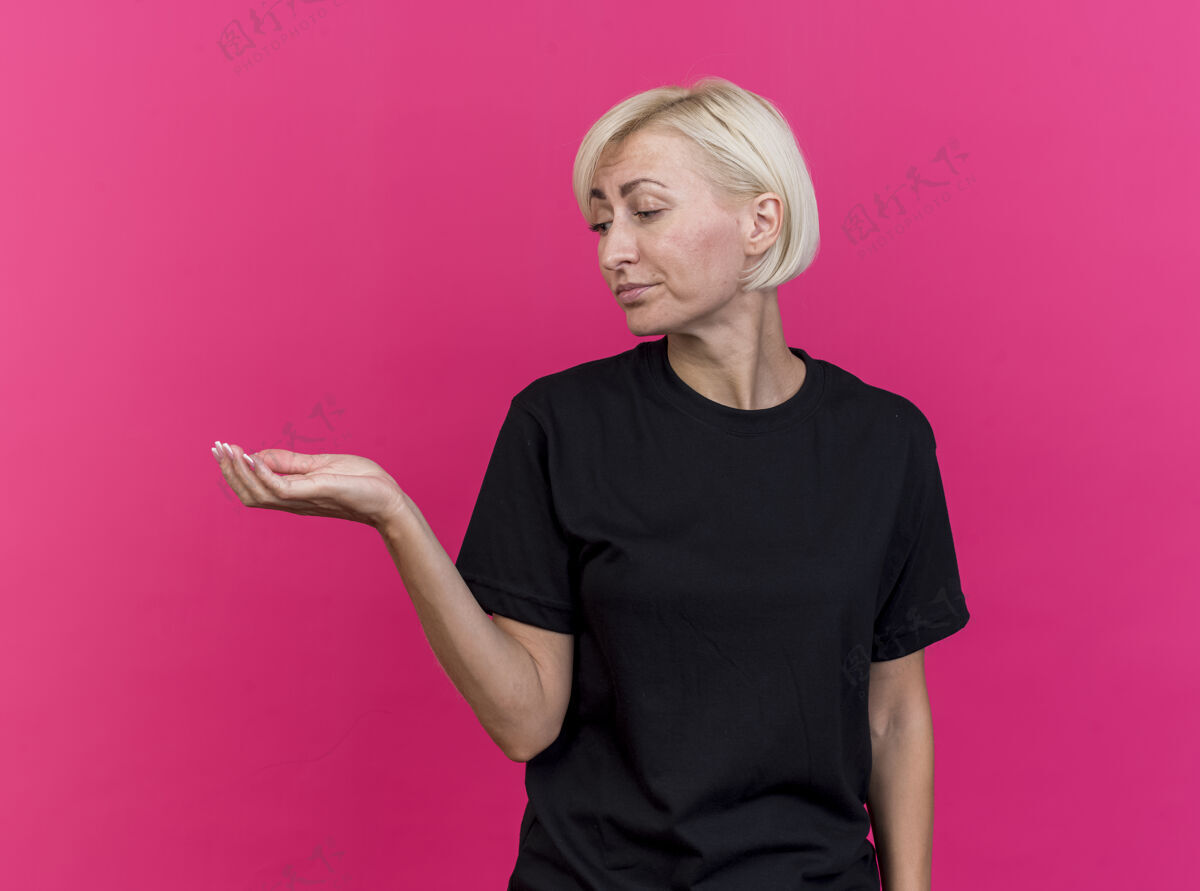 衣服一个中年金发斯拉夫女人 空着一只手 孤零零地站在粉红色的墙上看着它手空女人