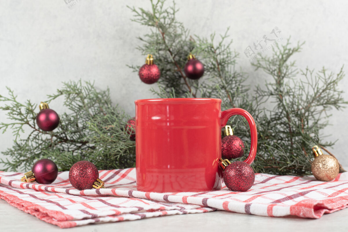 节日台布上的红色咖啡杯 有圣诞球和松枝圣诞节咖啡装饰