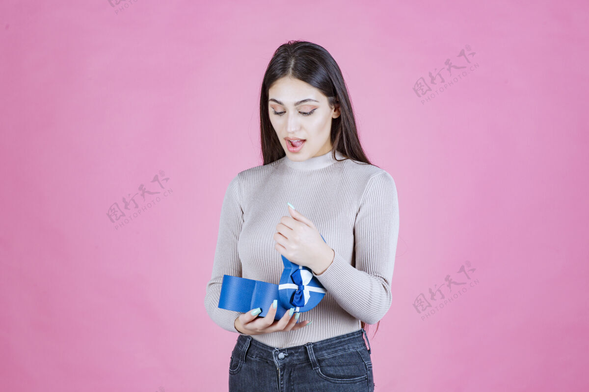 女性女孩检查她的蓝色礼品盒 看起来兴奋和惊讶姿势女人人