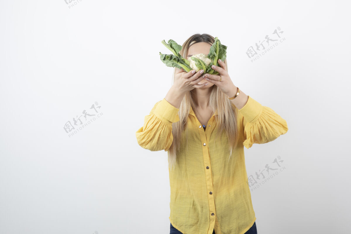 女人一个年轻漂亮的女模特站着用花椰菜遮住脸的照片女孩人类漂亮