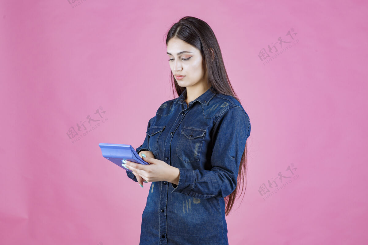 金钱女孩手里拿着一个蓝色的计算器在计算服装会计收入