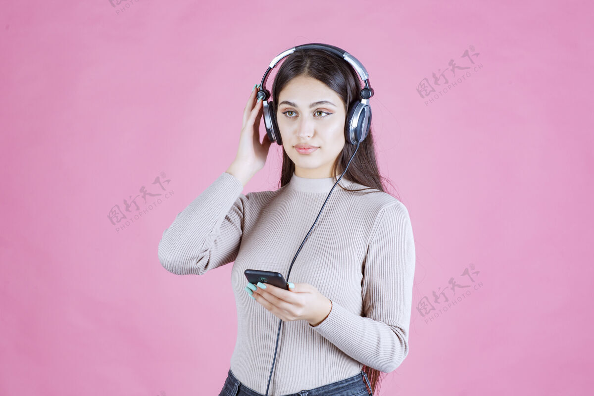 服装戴着耳机在智能手机前放音乐的女孩女人人类女性