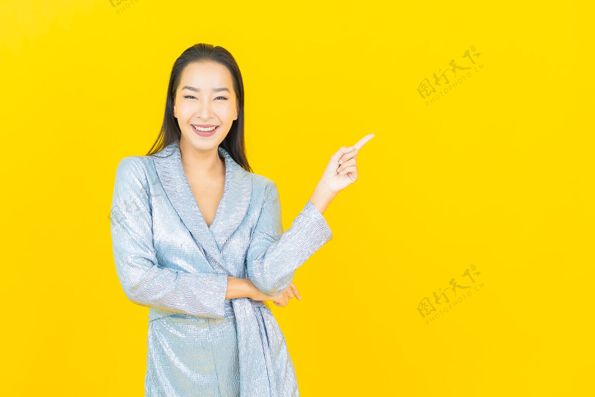 多彩在黄色的墙上描绘美丽的亚洲年轻女子微笑着行动休闲女孩肖像