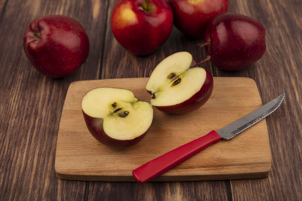 特写木制厨房板上半个红苹果的俯视图 刀上的苹果被隔离在木制背景上木头顶部木板