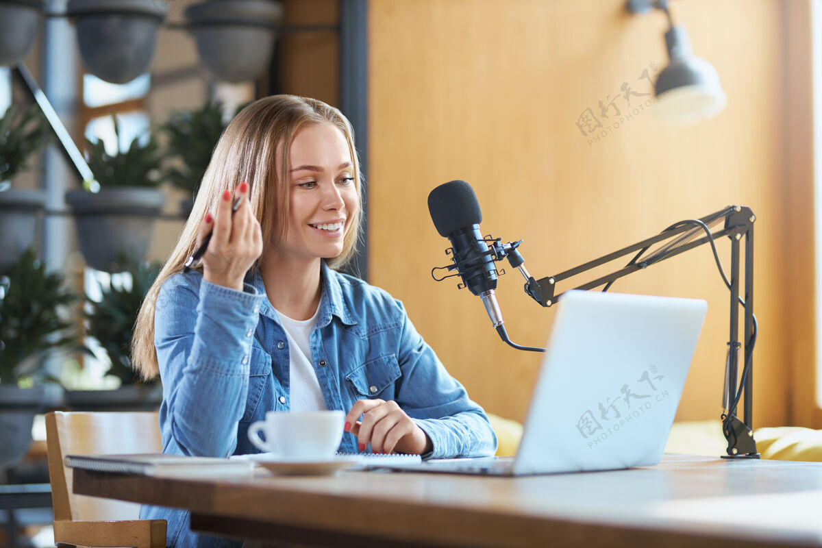 耳机在现场直播中 女人在笔记本电脑上讲信息咖啡广播通讯