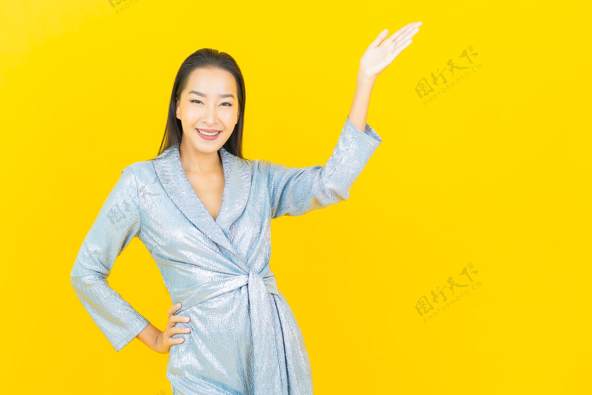 人在黄色的墙上描绘美丽的亚洲年轻女子微笑着行动展示年轻黑发