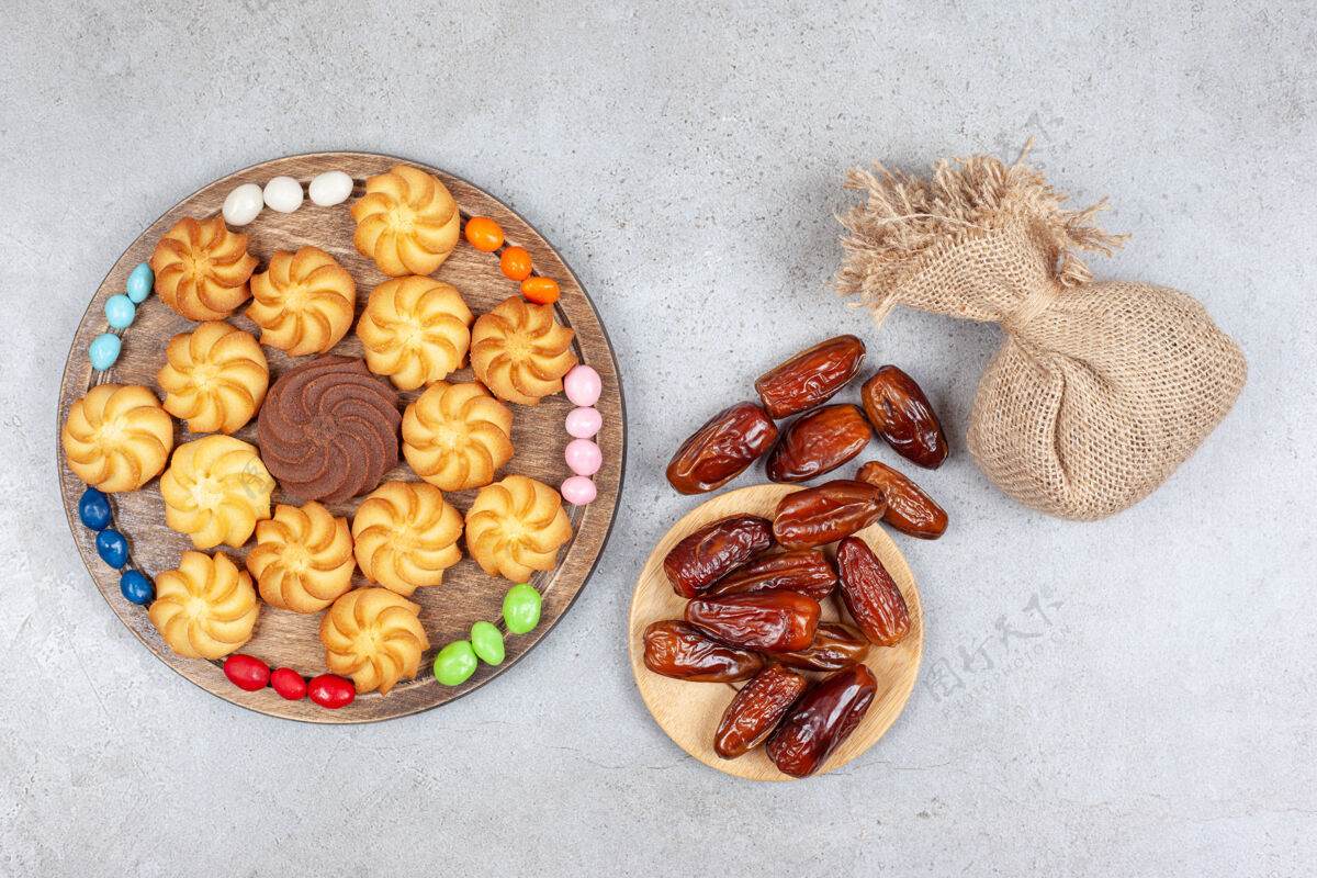 糕点一捆枣子和一个袋子 袋子里放着一块木板 木板上装饰着糖果和饼干 背景是大理石高质量的照片饼干袋子水果