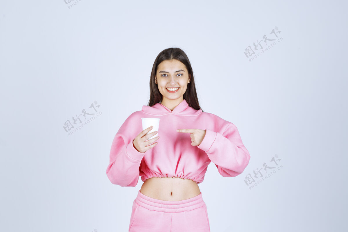 服装穿着粉色睡衣的女孩拿着咖啡杯指着什么东西女人积极休闲