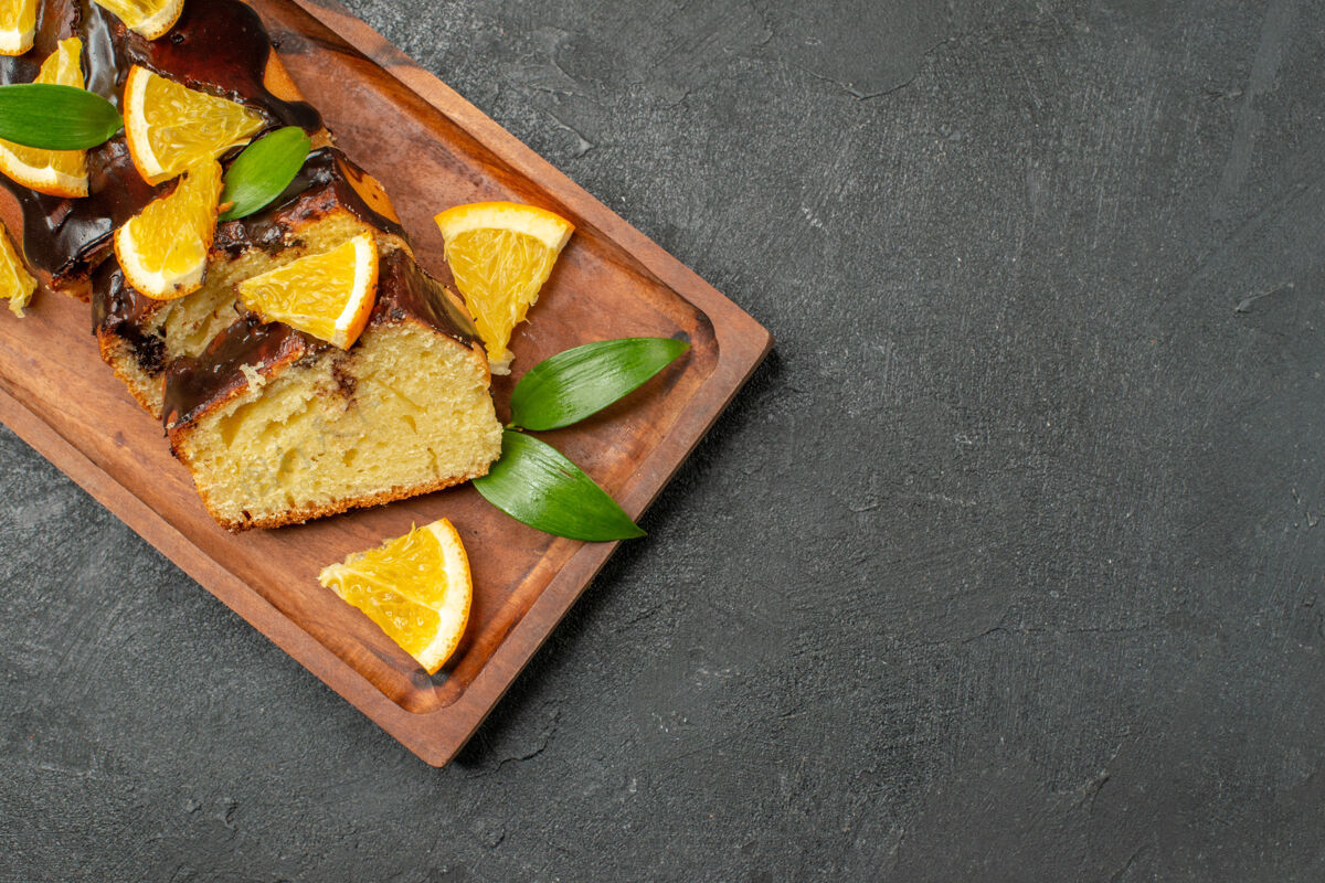 切美味的蛋糕装饰着橘子和巧克力在木制的砧板上放在黑色的桌子上美味蛋糕健康餐