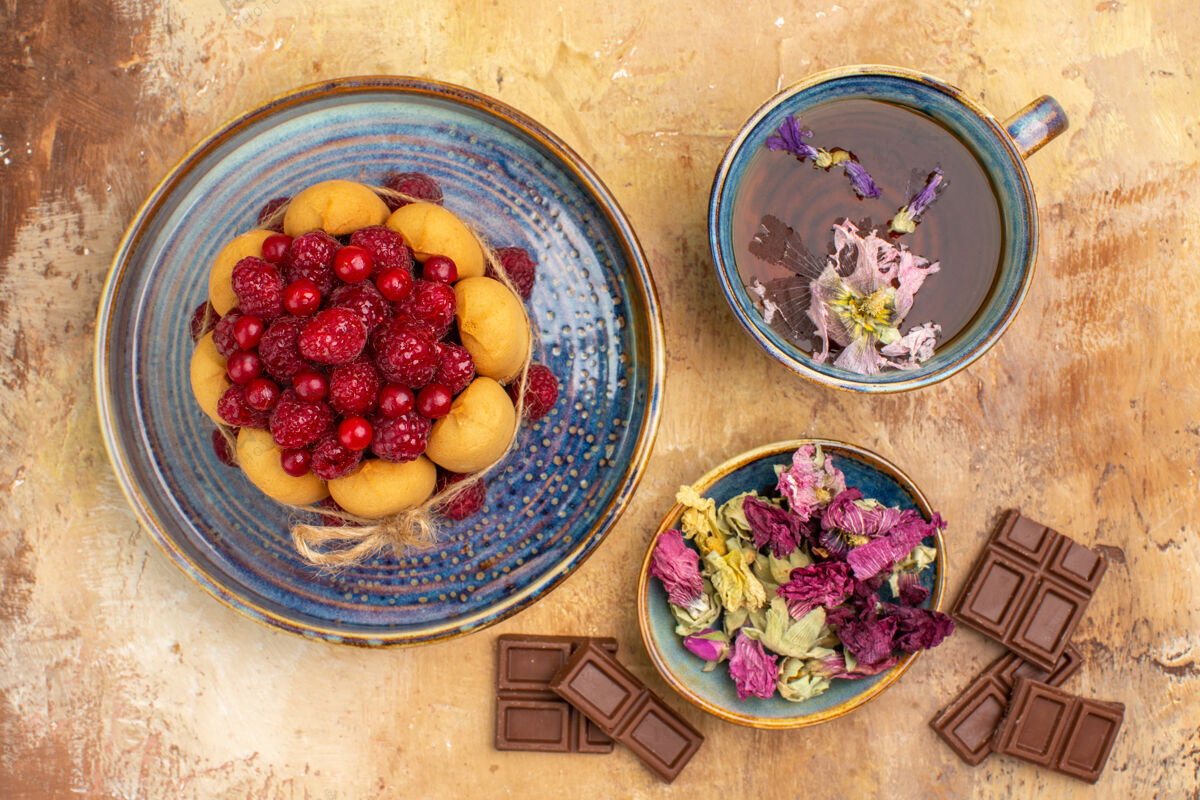 鲜花上图是一杯热花草茶 软蛋糕上有水果和鲜花 巧克力棒膳食可食用水果茶