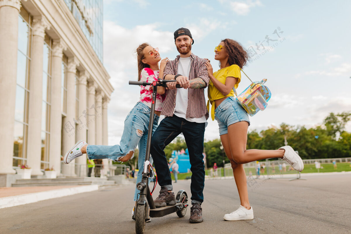 摩托车快乐的年轻朋友们带着电动脚踏车走在街上 男女同乐多民族积极友谊