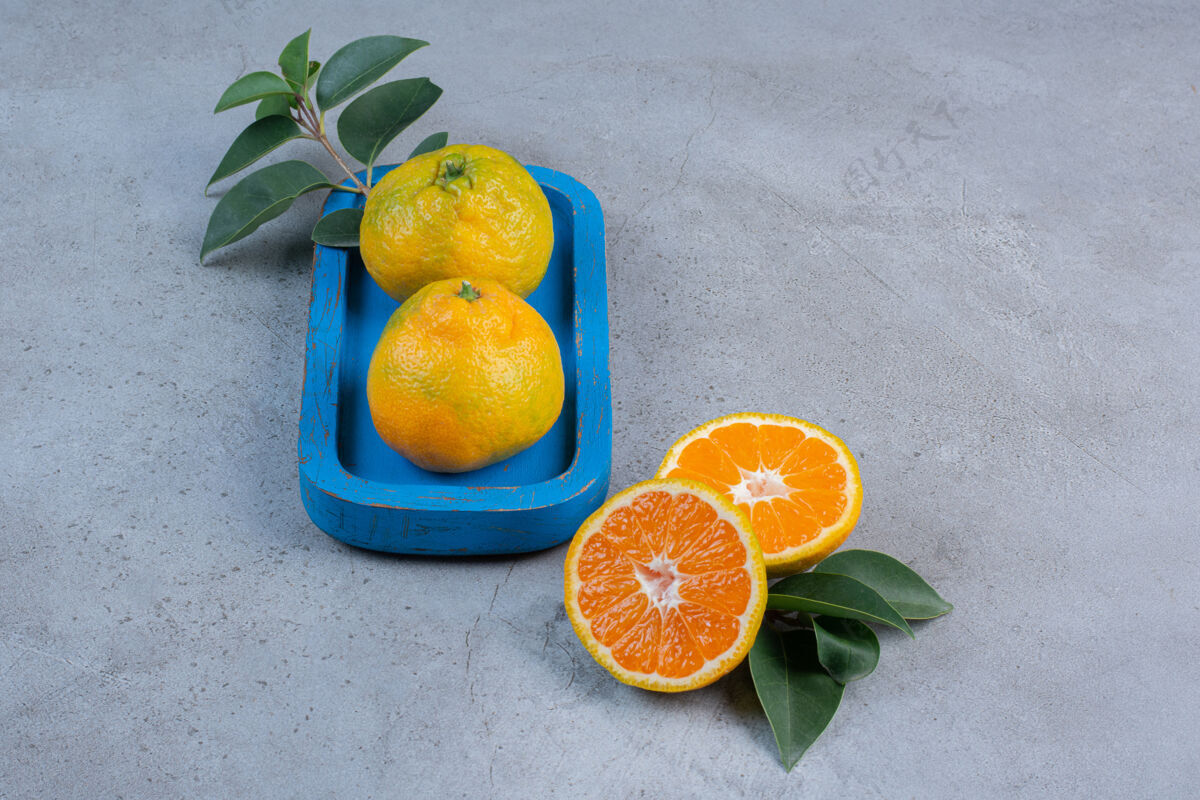 风味把一个橘子放在盘子里 旁边放着一片橘子叶 背景是大理石柑橘拼盘美味