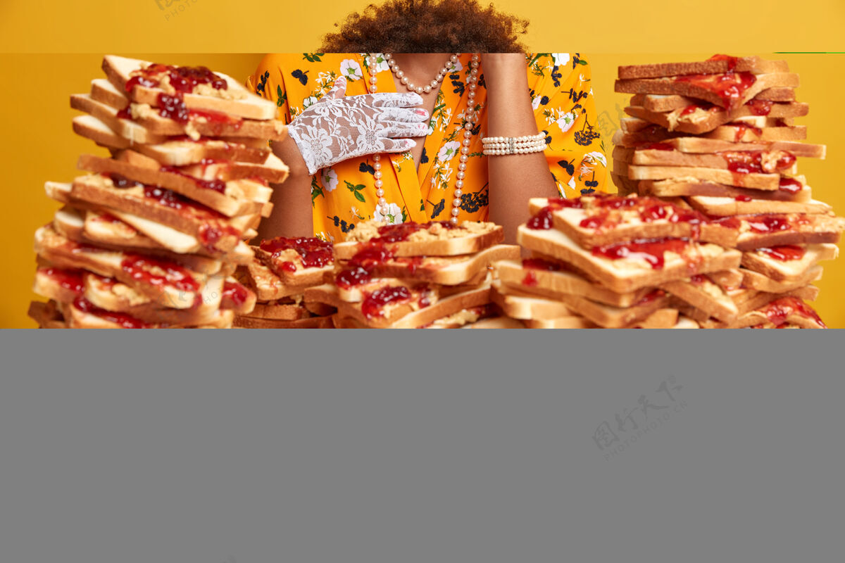 果酱喜出望外的优雅女士 一头非洲头发 微笑着 戴着时髦的太阳镜 对着一堆美味的三明治摆姿势黄色非洲堆