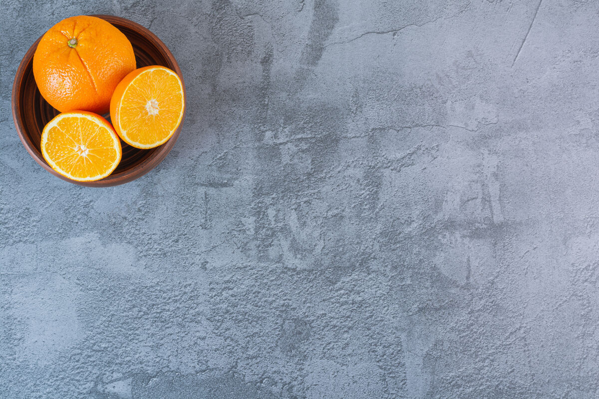 收获新鲜多汁的橙子在灰色的木碗顶视图水果多切割