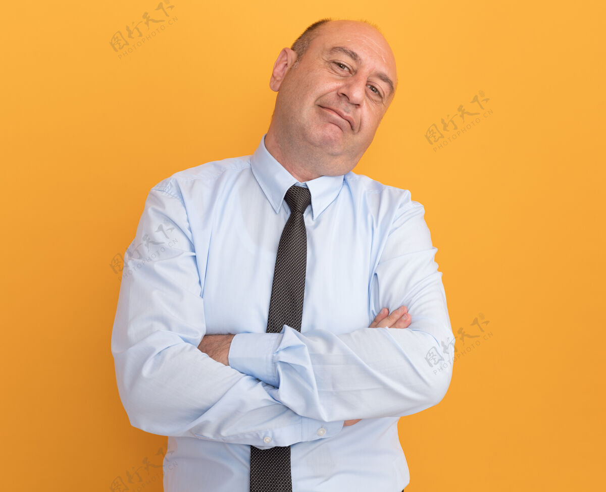 穿高兴的歪着头的中年男子穿着白色t恤 双手交叉打着领带孤立在橙色的墙上手头T恤