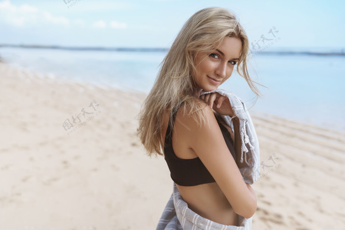 夏天温柔的金发女人转镜头微笑调情泳装热带海滩