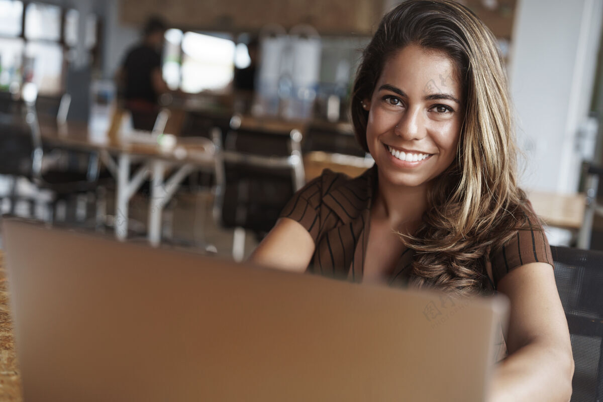 互联网成功的西班牙女人在咖啡馆用笔记本电脑微笑技术员工笔记本