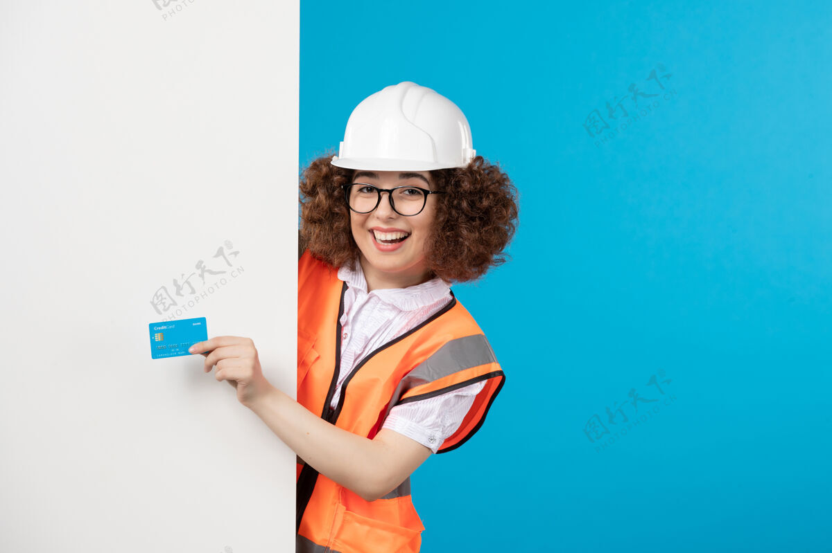 前面身着统一蓝墙的快乐女建设者正面图蓝色建筑商青年