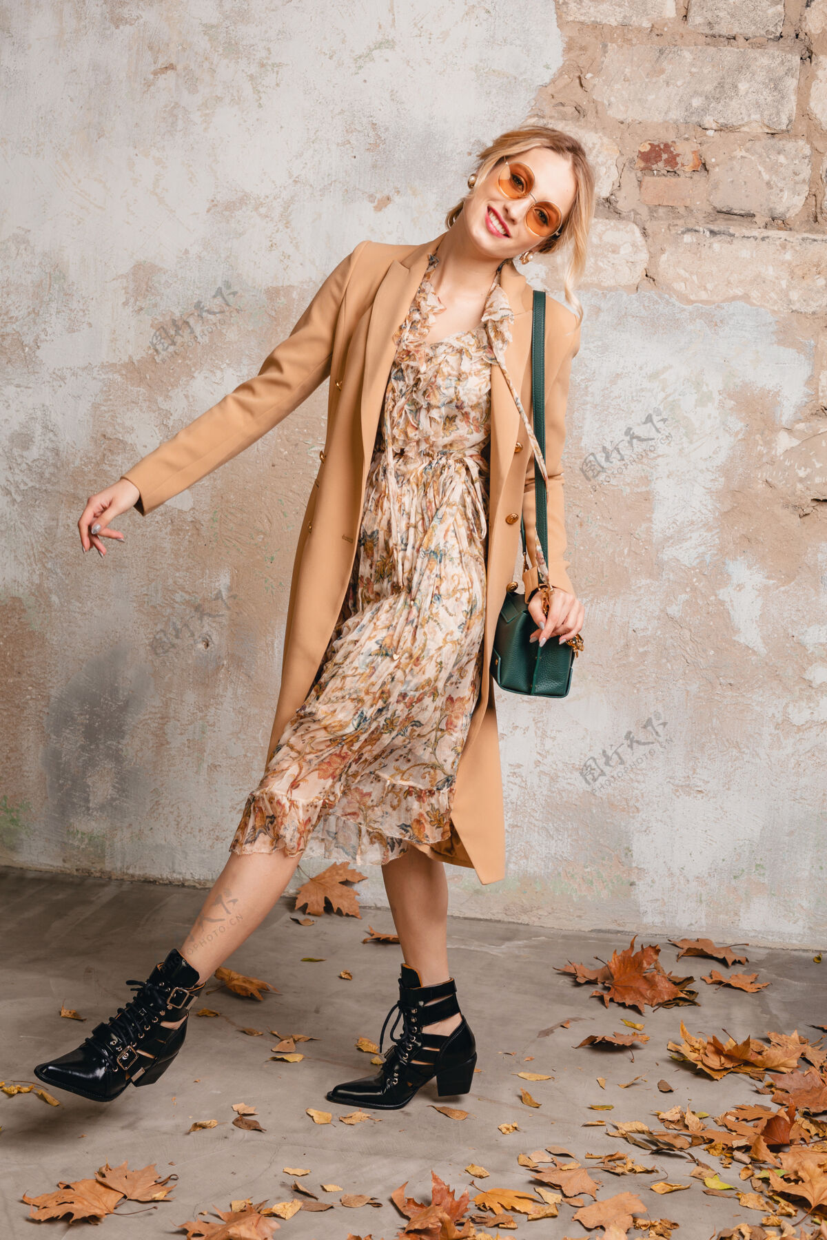 靴子穿着米色外套的迷人时尚金发女人在街上靠着老式的墙走着城市魅力休闲