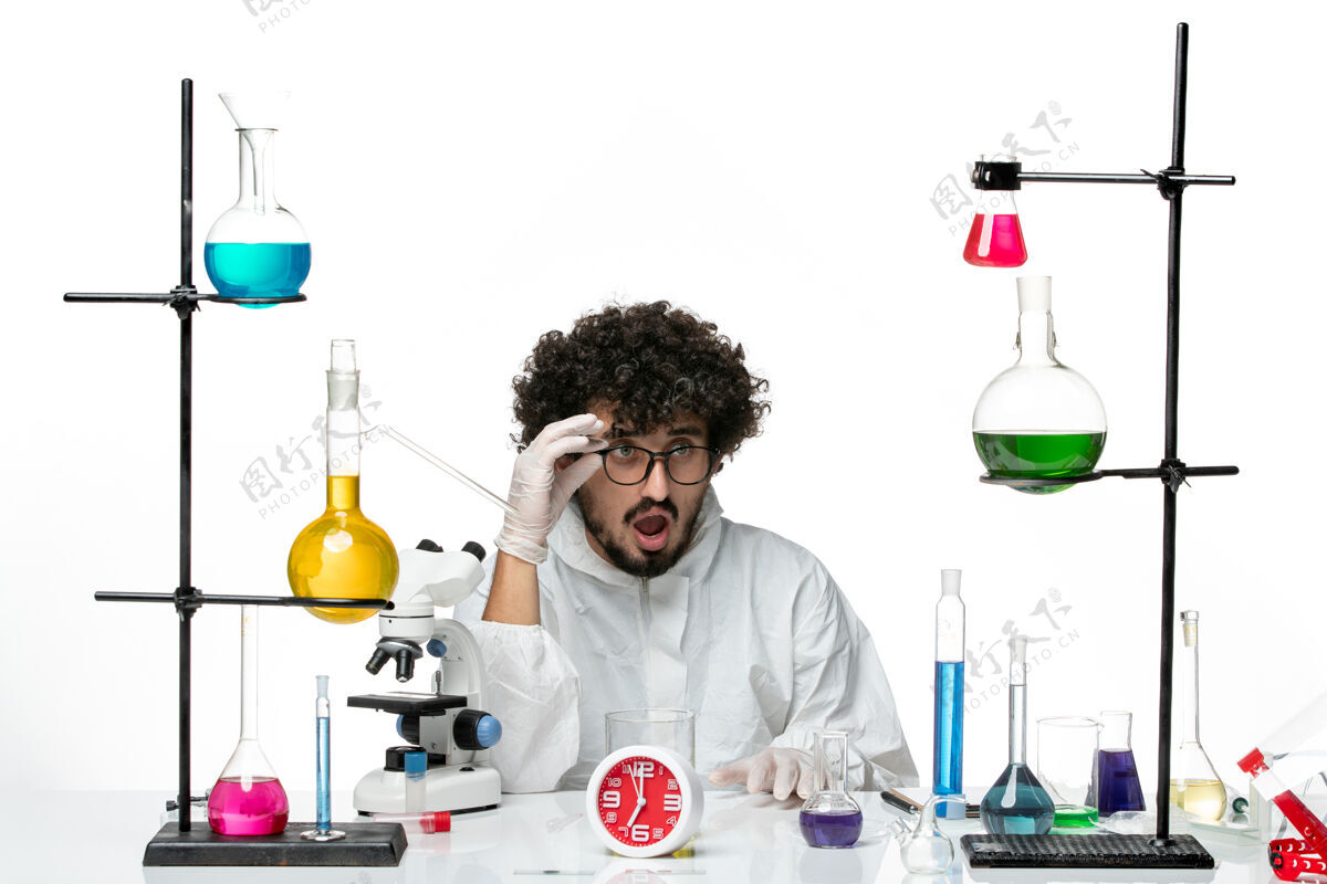溶液正面图穿着白色特别套装的年轻男科学家坐在那里 拿着解决方案特殊研究科学
