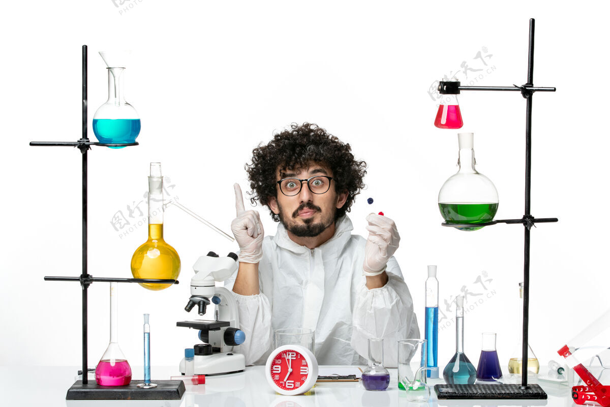 瓶子正面图身着特殊套装的年轻男性科学家在白墙上拿着样品烧杯玻璃研究