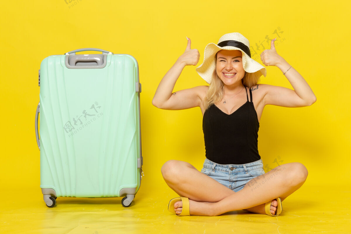 感情正面图年轻的女性坐在她的绿色袋子感觉快乐的黄墙旅行度假阳光旅行旅行女孩观点年轻身体