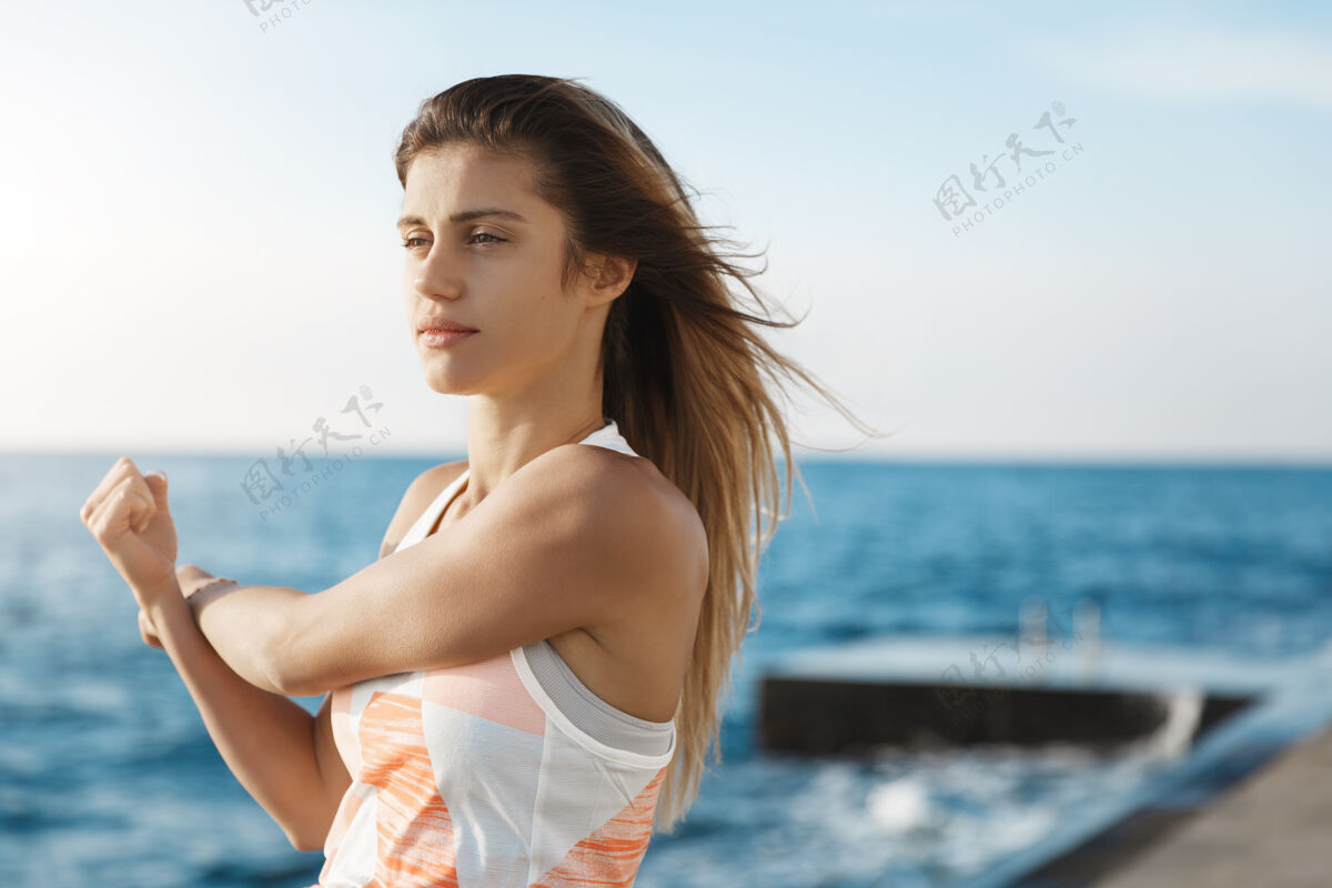 码头女人树立目标 保持身体健康 伸展双臂 做慢跑热身运动 看起来决心十足瑜伽码头健身