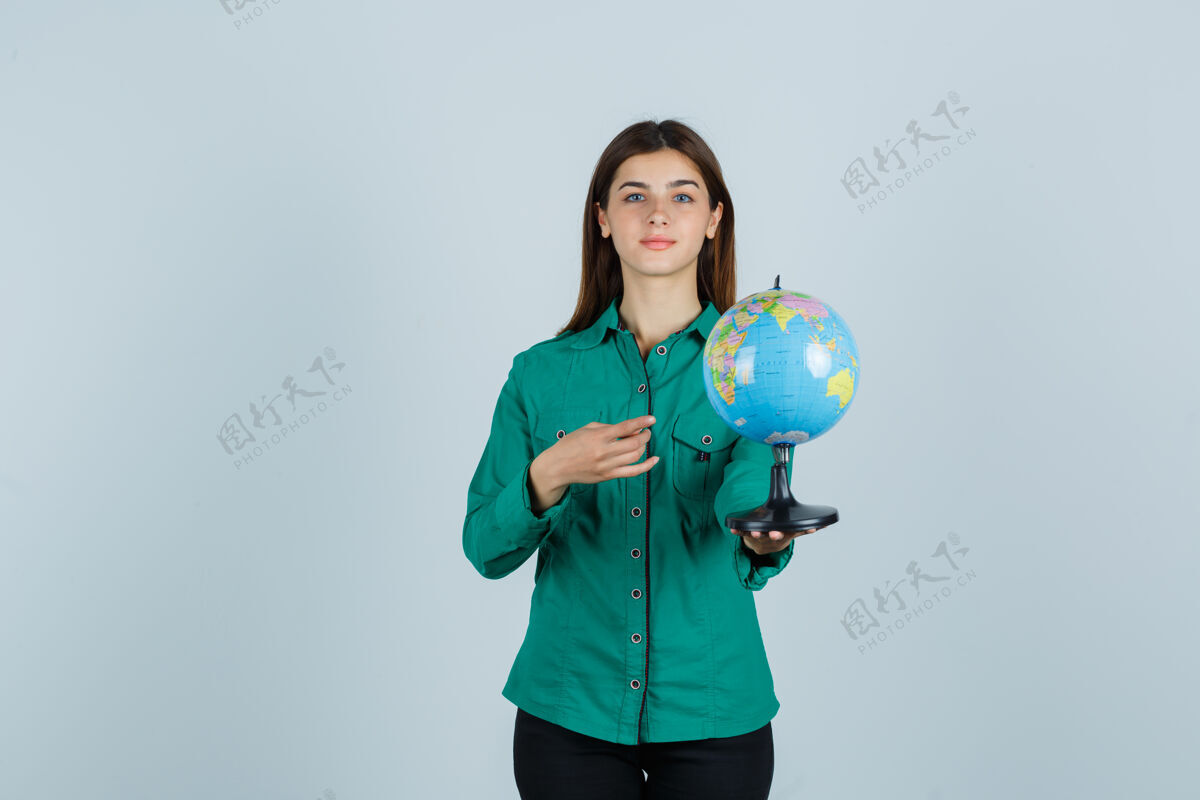 前面穿着衬衫的年轻女士拿着地球仪 指着地球仪 看上去很自信 正对着地球仪眼睛头发黑发
