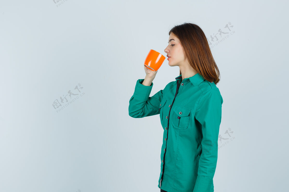 女性年轻的女士穿着衬衫 喝着橘色茶杯里的茶 目光集中 俯瞰前方女孩夏天魅力