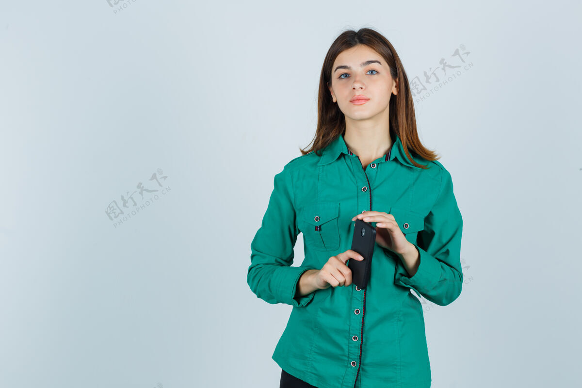 金发穿着绿色衬衫拿着手机的年轻女士 看起来很理智正面视图年轻人模特
