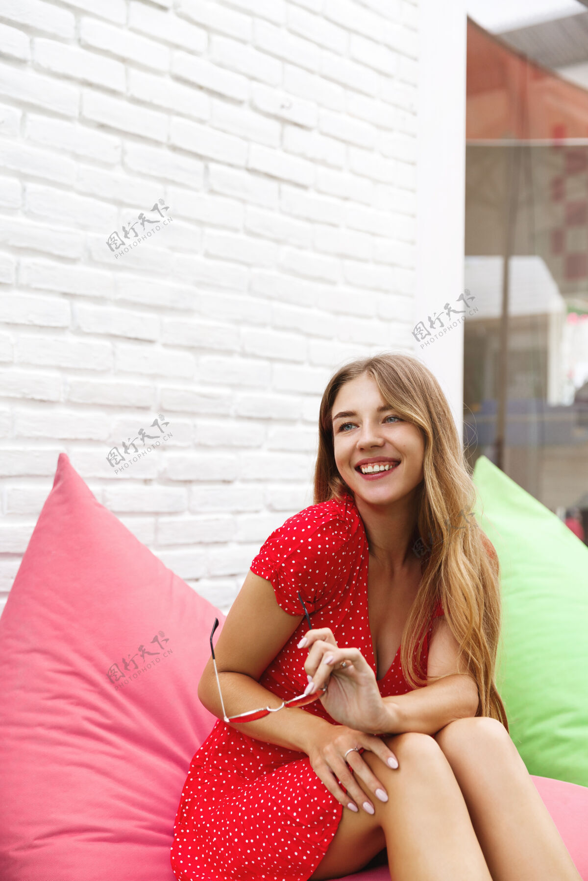 休闲一个美女坐在豆包椅上 在户外咖啡馆玩得很开心的垂直镜头享受女孩砖墙