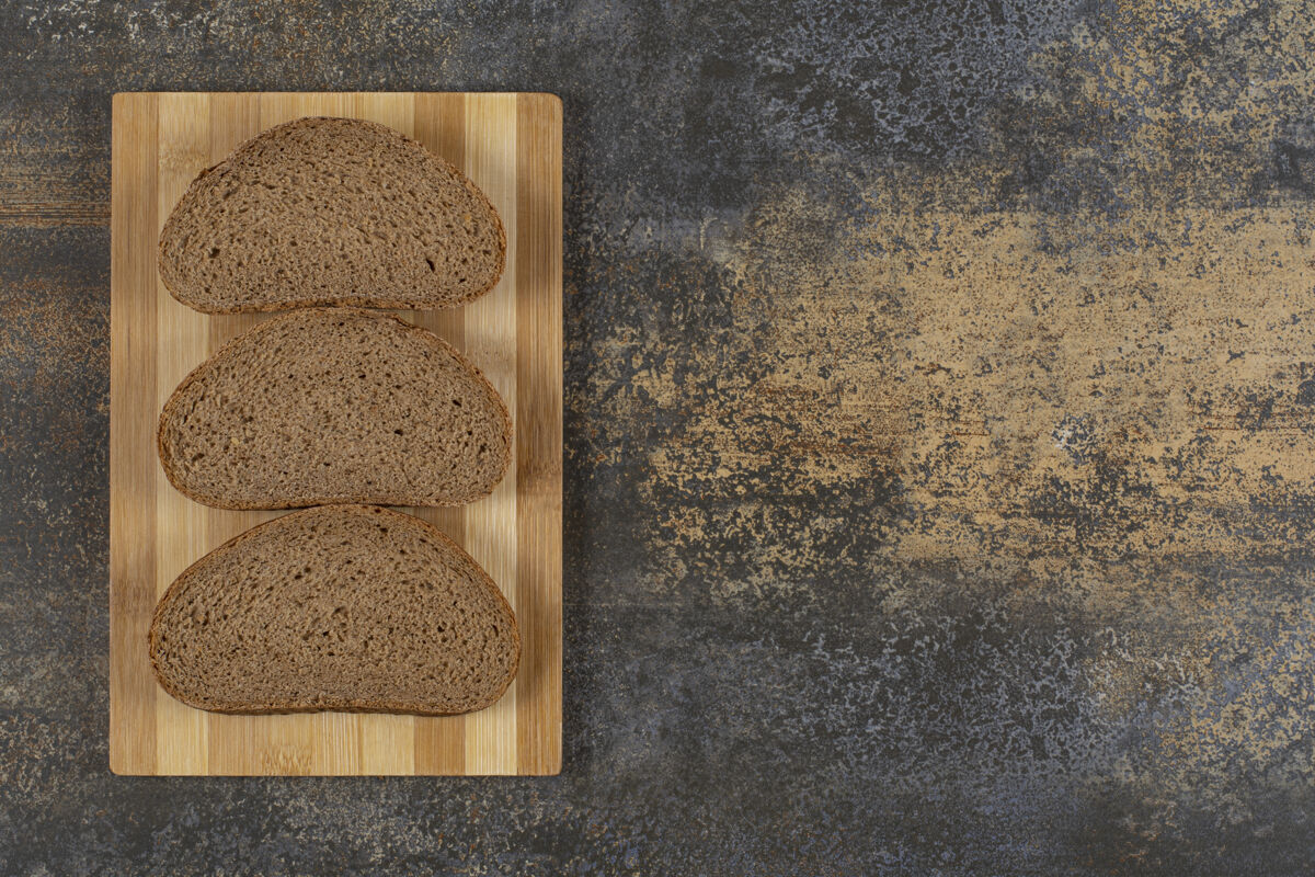 深色三片黑面包放在木板上黑麦营养面包
