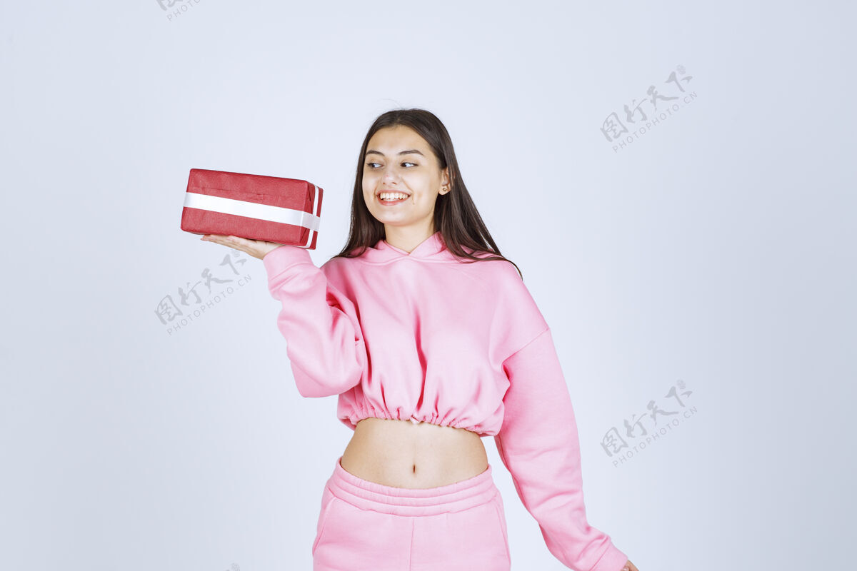 姿势穿着粉色睡衣的女孩手里拿着一个红色长方形礼盒 看上去很满意积极人类人体模型