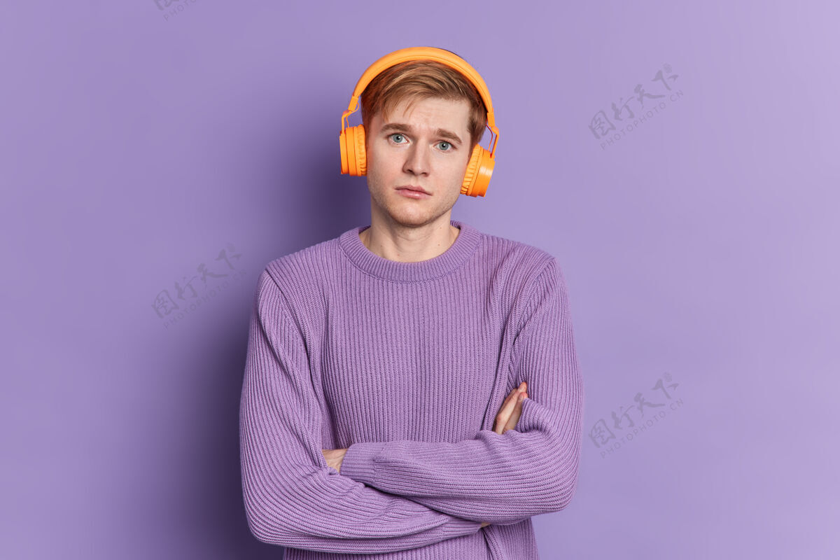 完美严肃帅气的少年男孩的画像交叉双臂站在镜头前 戴着耳机和套头衫摆姿势男人耳机休闲
